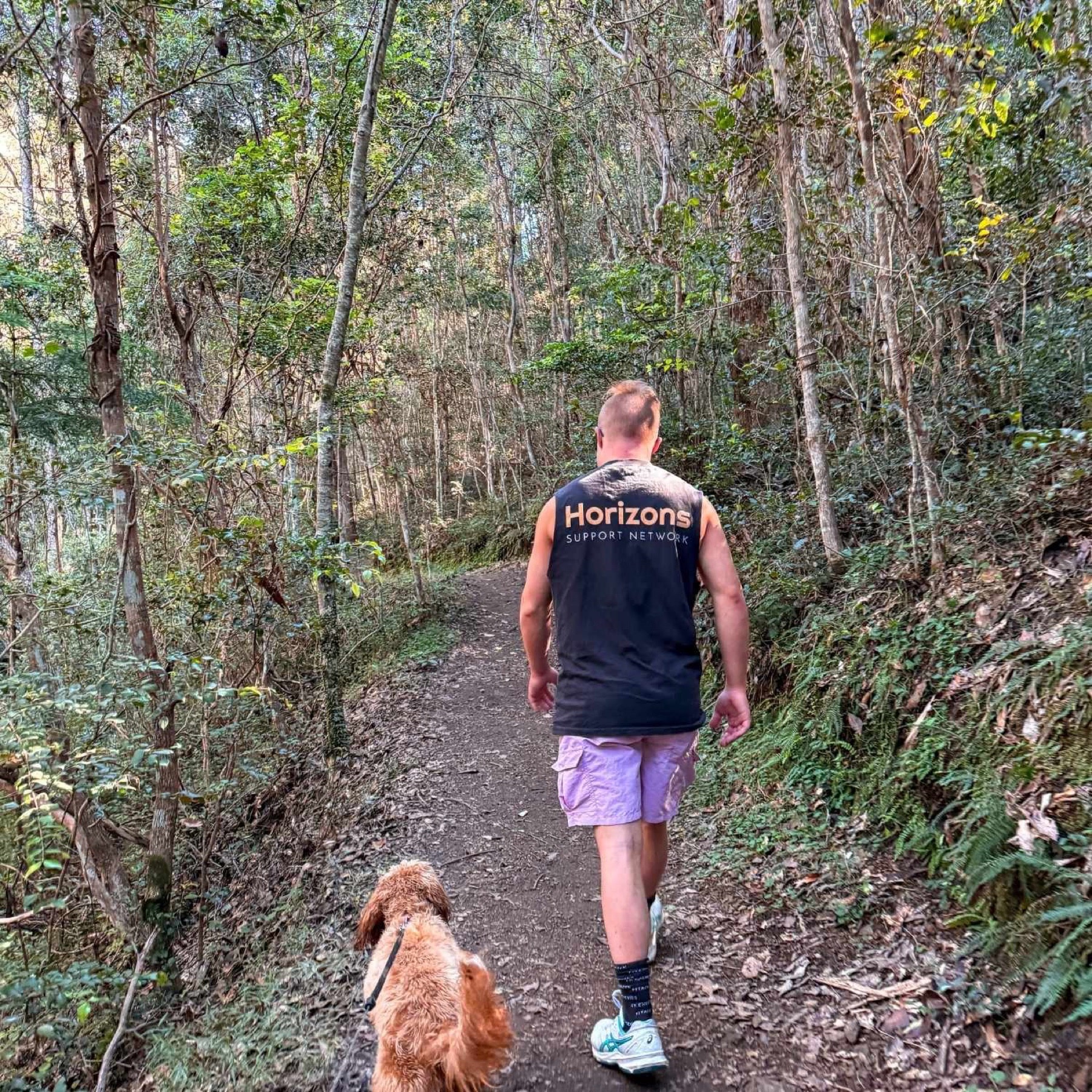 A person walking a dog on a bush trail