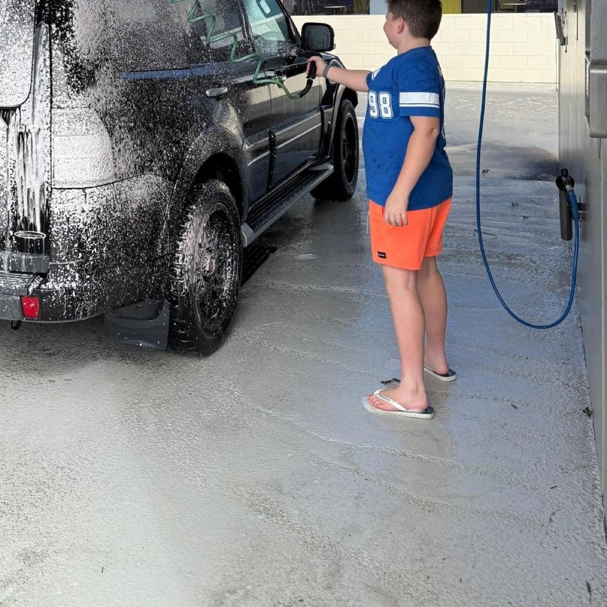 A person washing a vehicle at a self-service car wash